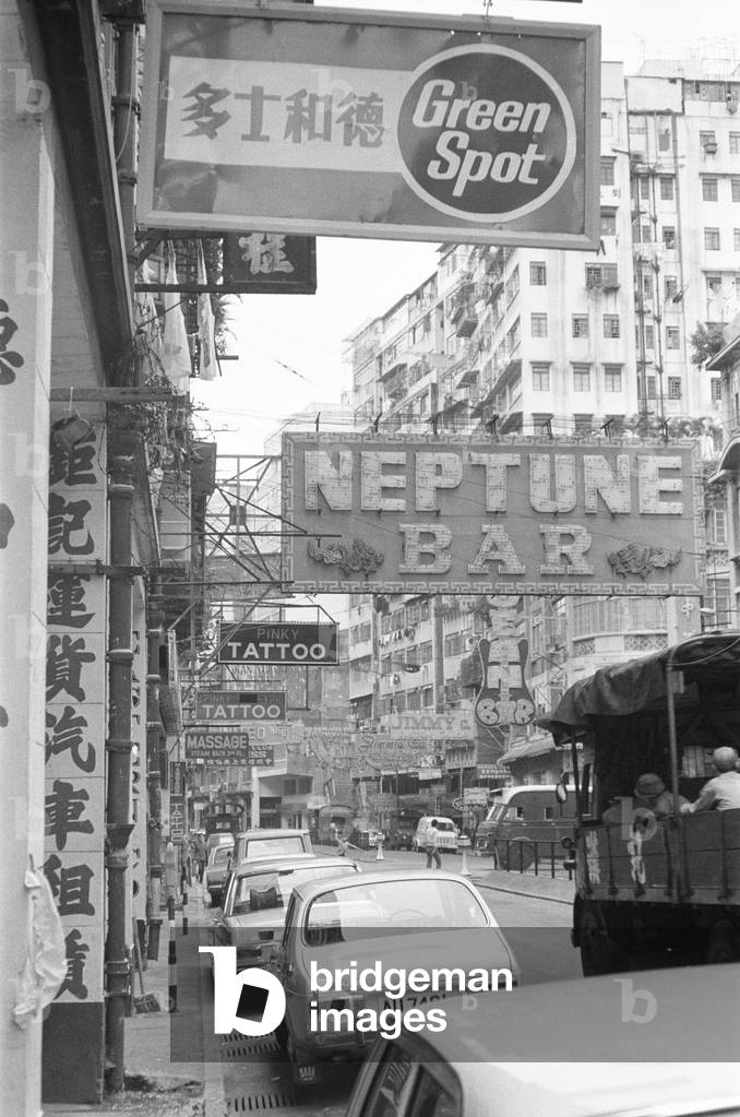Traffic and signs advertising night clubs, tattoo and massage parlours seen here on Lockhart Road, Wanchai, Hong Kong. September 1974 (b/w photo)
