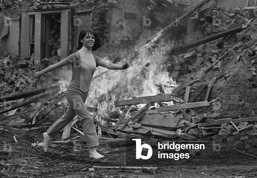 Actress Wendy Padbury, running past a collaped building, the ruins of which are on fire - 1968 Wendy played Doctor Who companion Zoe Herriot, 1968 (b/w photo)
