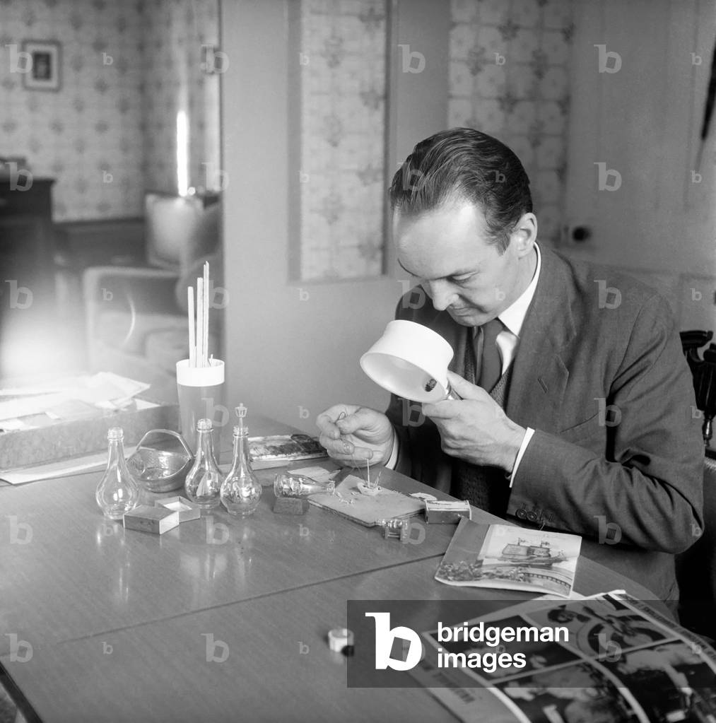 Man creating a ship in a bottle model: 1965 (b/w photo)