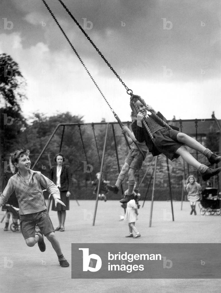 Two boys playing on swings in the playground, 10th July 1942 (b/w photo)