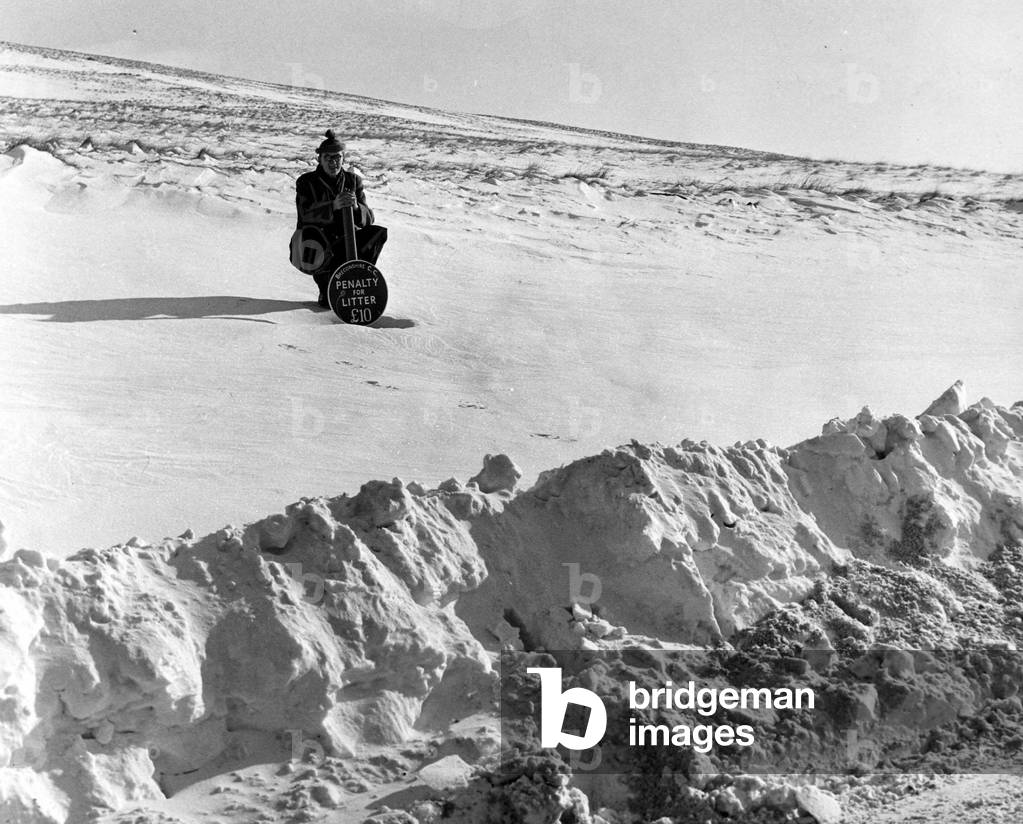 Under the sign 'Penalty for littering' there is at least eight feet of hard snow. This picture was taken on a mountain road in the Brecon Beacons and shows where a lay-by used to be. 13th January 1963.