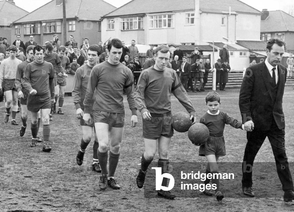 Remembrance is written on the faces of Highgate United Captain, Gordon Cooper, six-year-old mascot Anthony Doherty - son of Highgate half-back Hughie - and manager John Hewitson as they take to the field for todays game. Highgate's Tony Allden was killed after being struck by lightning the month before. 4th March 1967 (photo)