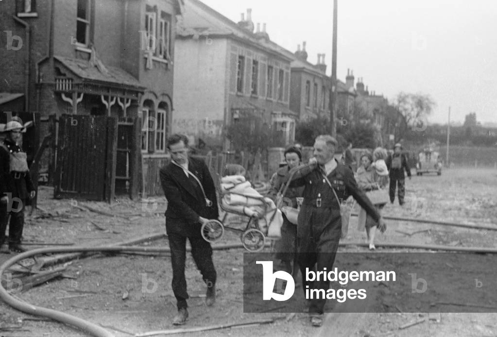Alfieri. Air Raid damage at Malden, London. Two men give a helping hand to a young girl in her makeshift pram, August 16th 1940