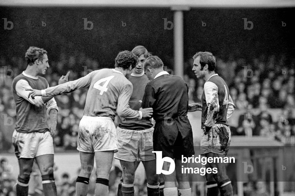 Arsenal v. Manchester City. Doyle (No. 4) of City appeals to refree Wallace after Wallace had booked George of Arsenal for substituting without permission. December 1969 (photo)