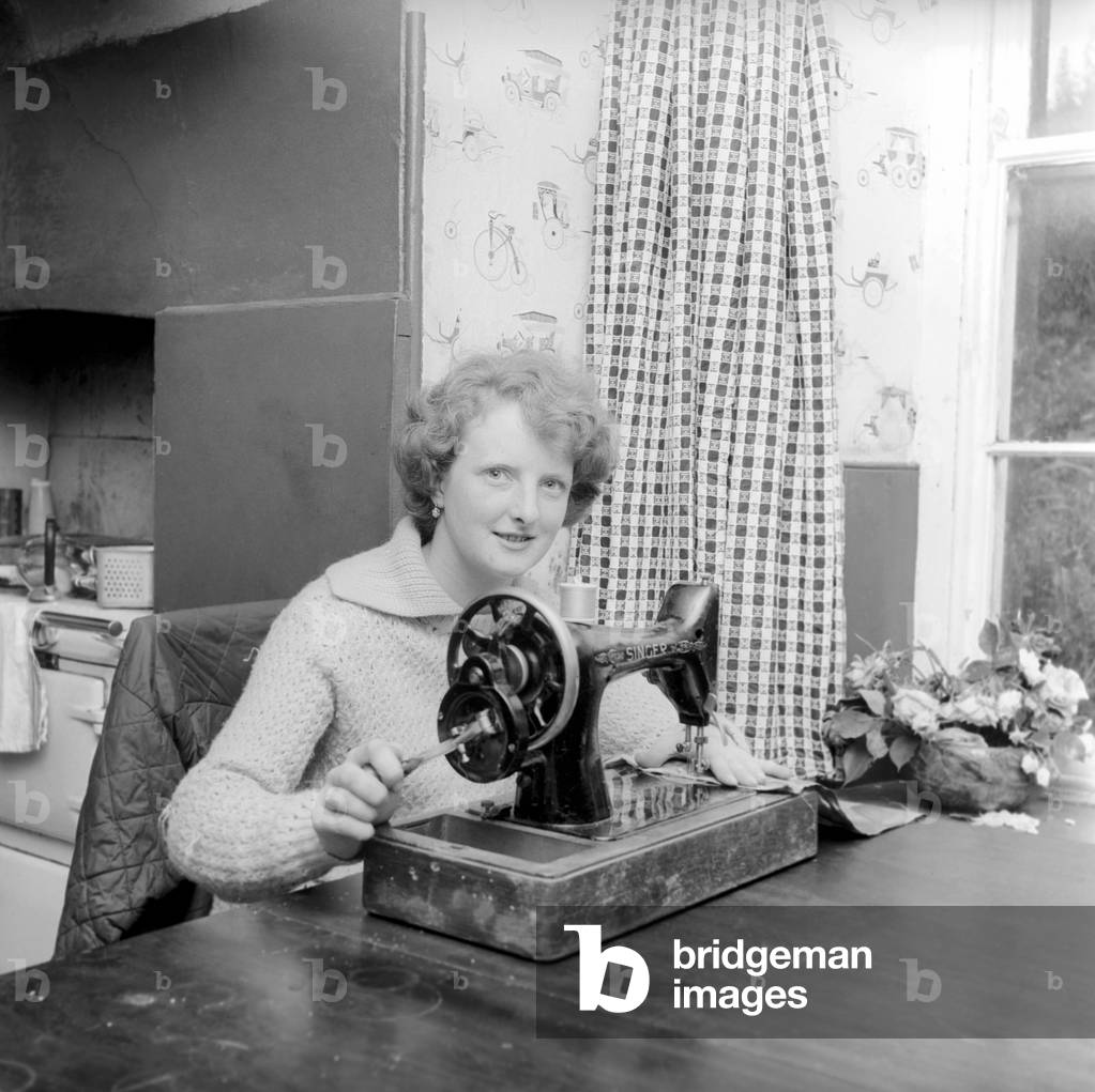 Woman using sewing machine. Circa 1964