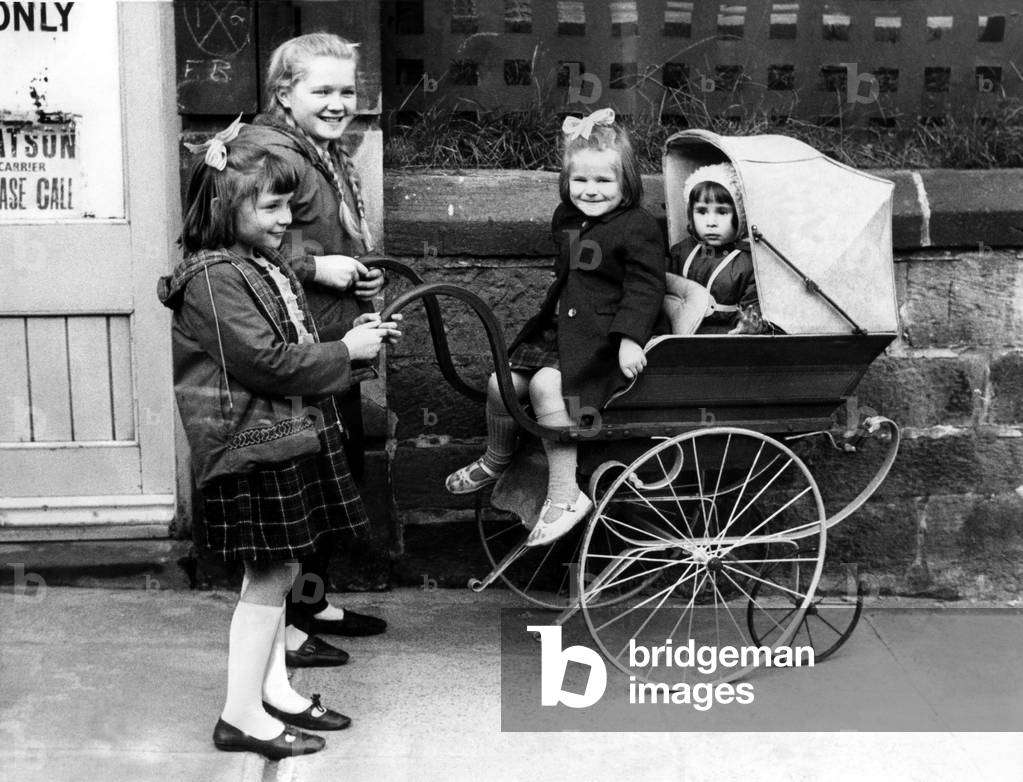 Linda Carruthers, Valerie Harrison, Gilliam Carruthers and Allison Caruthers trying out the comfort of a Victorian pram on 28th October 1965 (b/w photo)