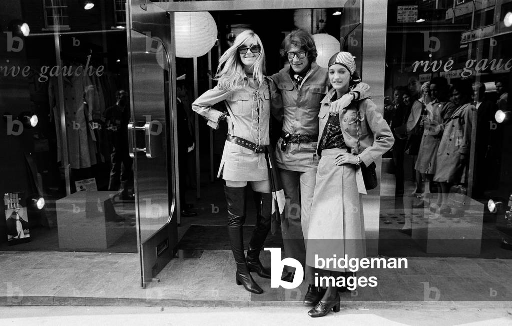 Yves Saint Laurent, designer pictured outside his first London Rive Gauche store on New Bond Street, London, opening day of boutique, and with muses Louise de La Falaise, aka Loulou (right) and Betty Catroux (left). 10th September 1969 (b/w photo)