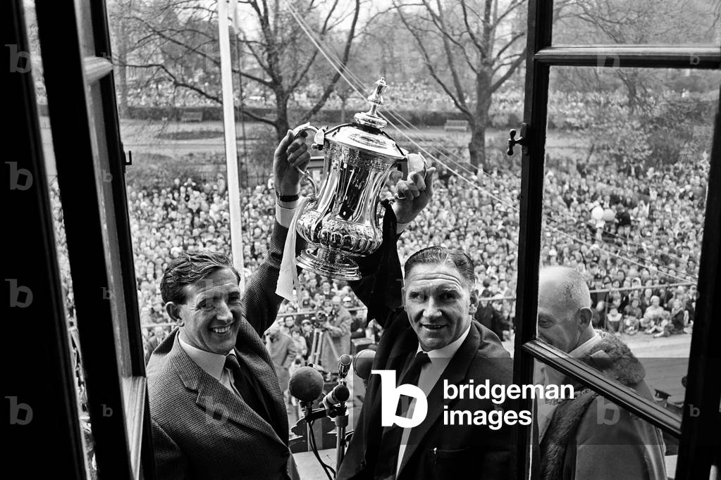 Tottenham Hotspur players parade the FA Cup trophy from the top of an open top double decker bus to thousands of fans gathered in the streets of North London. Spurs defeated Burnley 3-1 in the Final at Wembley. Captain Danny Blanchflower and manager Bill Nicholson proudly hold the trophy aloft. May 1962 (photo)