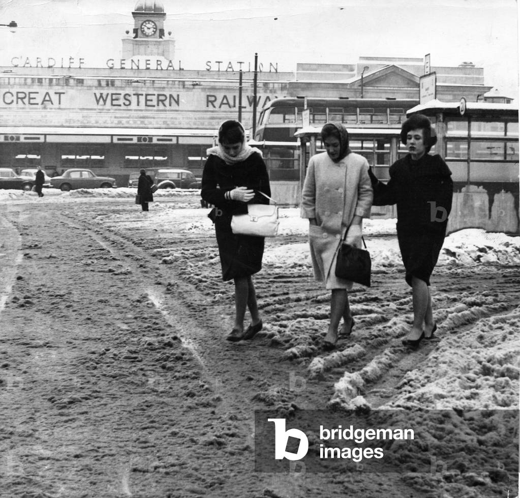 Weather - Three girls swish through the slush at Cardiff's Central Bus Station with the railway station in the background - 2nd February 1963.