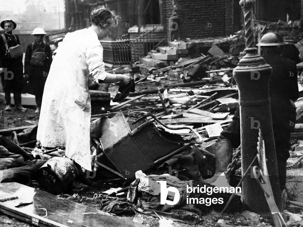 Bomb damage in Liverpool during the Second World War. A woman searches the wreckage of her home for belongings, after a German raider had dropped bombs on it during a raid to a block of flats in Belvidere Road, Liverpool., 27th September 1940 (b/w photo)