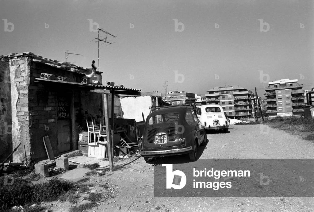 Housing and motor cars in a poor suburb on the outskirts of Rome, Italy, April 1975 (b/w photo)
