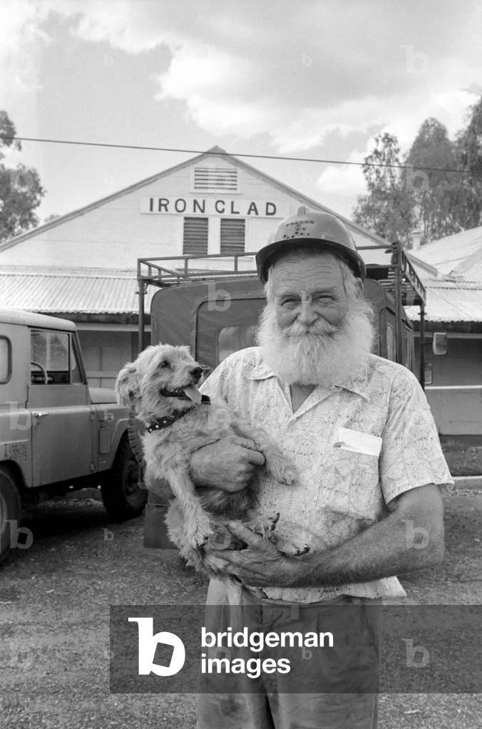 Marble Bar Western Australia: 68 year old Ken Macpherson with his 13 year old dog Spondulix a constant companion on his gold mining expeditions, outside the Ironclad, April 1977 (b/w photo)