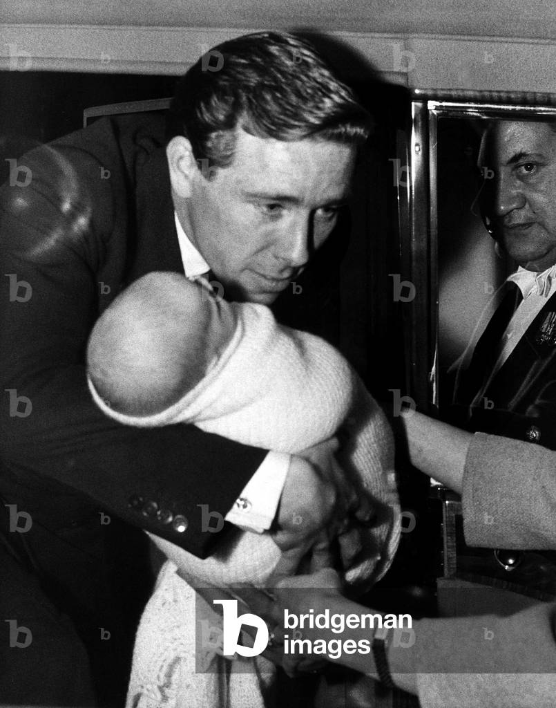 Lord Snowdon hands over Viscount Linley to Princess Margaret, already seated in the car, November 1961 (b/w photo)