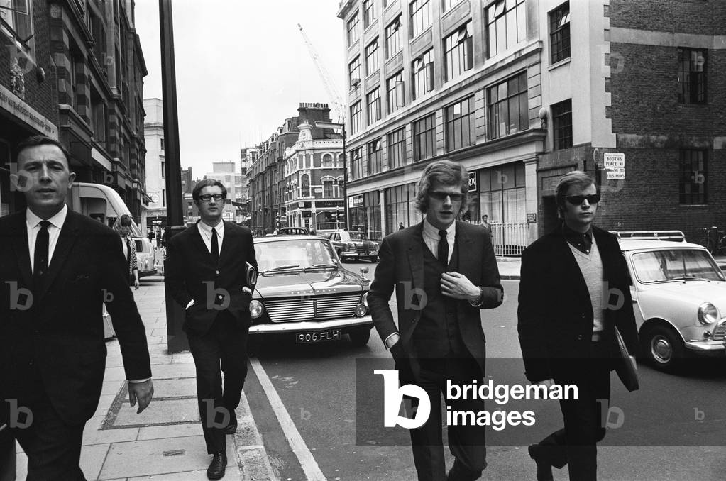 The Rolling Stones manager Andrew Loog Oldham (centre) on his way to Wells Street Court, London, charged with a traffic offence. On his right is Reg Stiles, his chauffeur.7th July 1965.