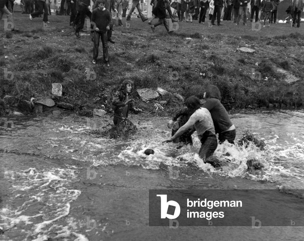Anything can happen when the lads play Uppies and Doonies . . . including a dip in the nippy river water. April 1974