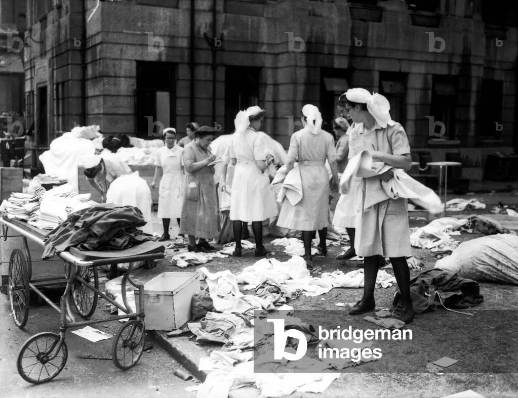 Nurses sorting linen outside Lewisham hospital after raid on the hospital the night before, July 1944 (b/w photo)
