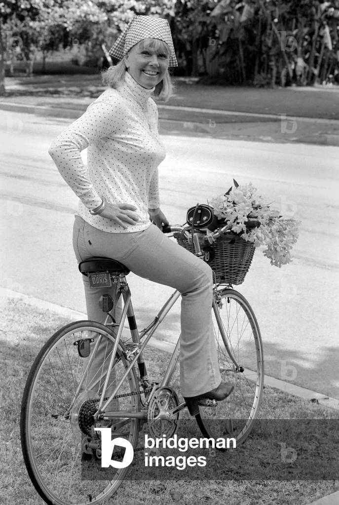 Doris Day seen holding a bunch of flowers on her bicyle, which she rides every day to keep fit. 
26th August 1980.