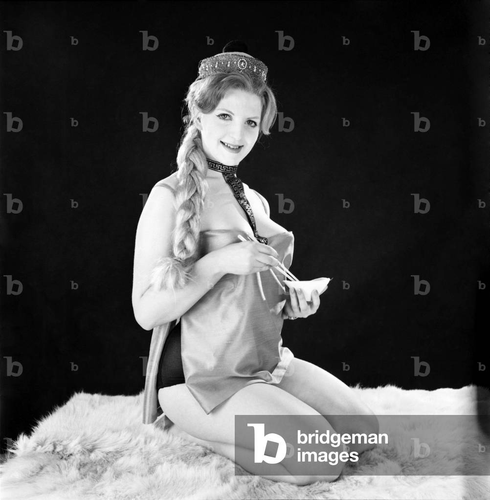 Model Peggy Cage seen here modelling a Chinese style outfit in the Reveille studios, 1962 (b/w photo)