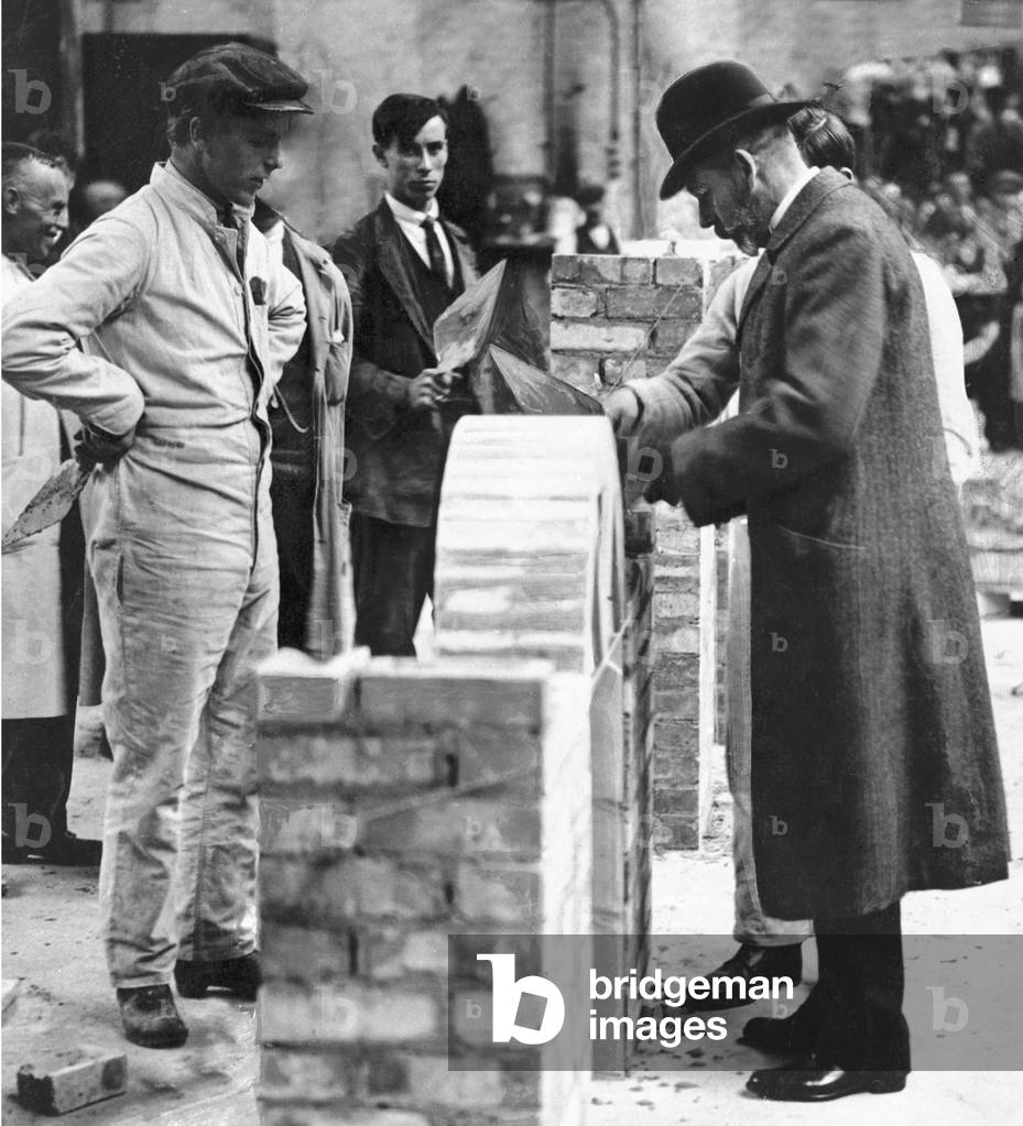 King George V tries his hand at brick laying during a visit to the Government Instructional Factory for ex-servicemen in Cricklewood 7th June 1920 (b/w photo)