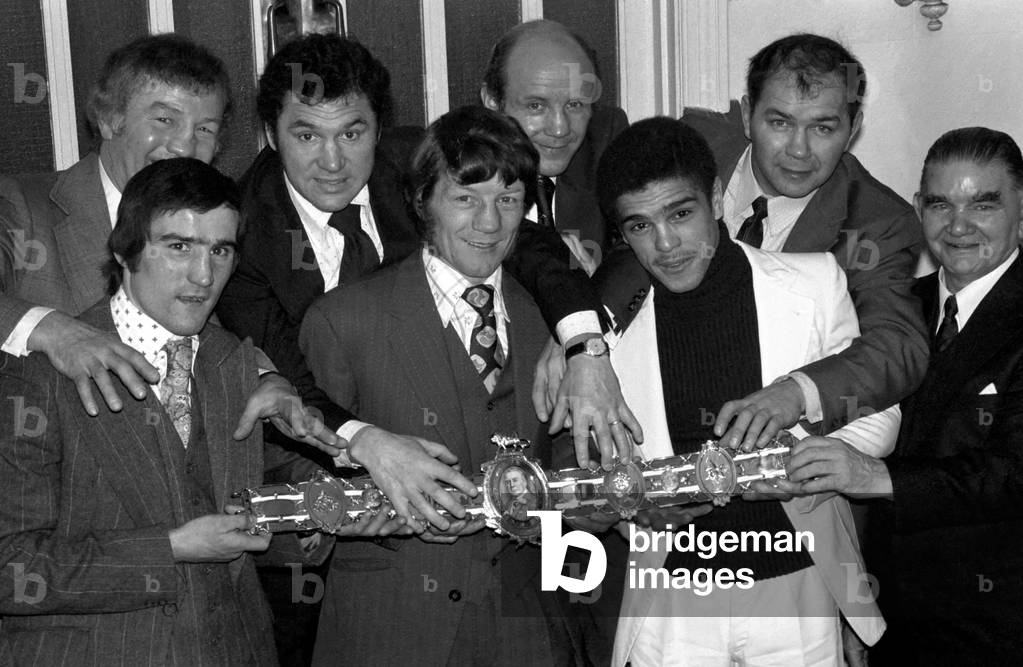 Ex-World Featherweight World Champion, now retired, Evan Armstrong trying to keep Jimmy Revie (left) and Vernon Sollas away from his Lonsdale Belt, March 1975 (b/w photo)