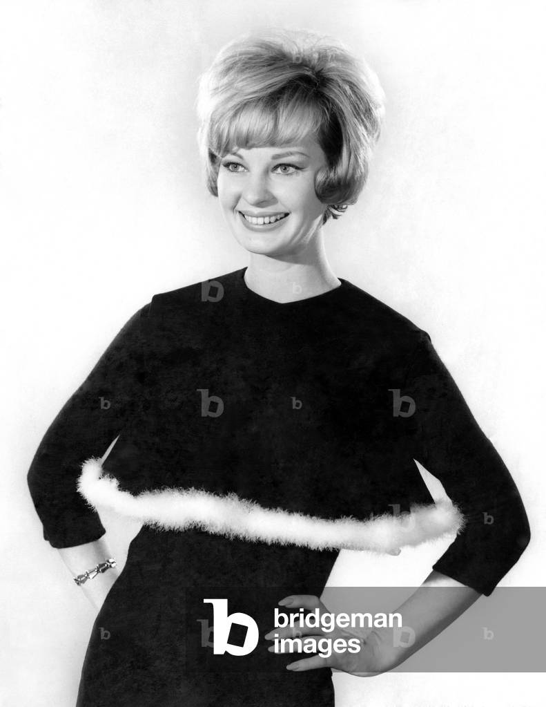 Model Dawn Chapman wearing a black long sleeved top with white fur trim. 
December 1961