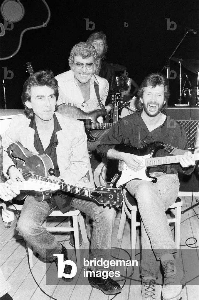Carl Perkins assembled himself a super backing group at Channel 4's Limehouse Studios for a television programme 'Blue Suede Shoes'. Left to right: Beatles guitarist George Harrison with Carl Perkins and Eric Clapton. 21st October 1985 (b/w photo)