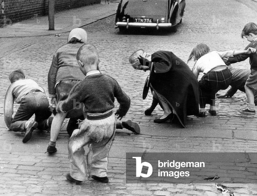 An adult joins in the fun as the youngsters scramble for the pennies after a wedding hoy oot, 1963 (b/w photo)