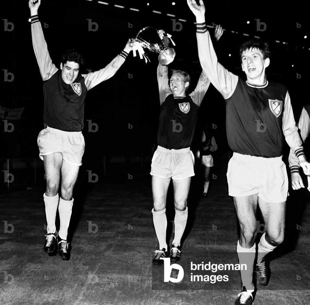 European Cup Winners Cup Final at Wembley Stadium. West Ham United 2 v 1860 Munich 0. Hammers captain Bobby Moore holds aloft the trophy with two goal hero Alan Sealey on a lap of honour after the match. Right is teammate Martin Peters. 19th May 1965 (photo)