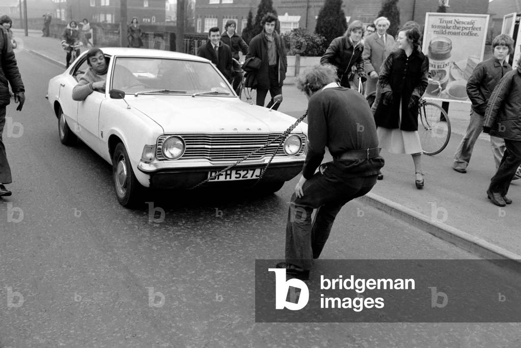 Strongman Reg Morris pulls car and passengers with his teeth, February 1975