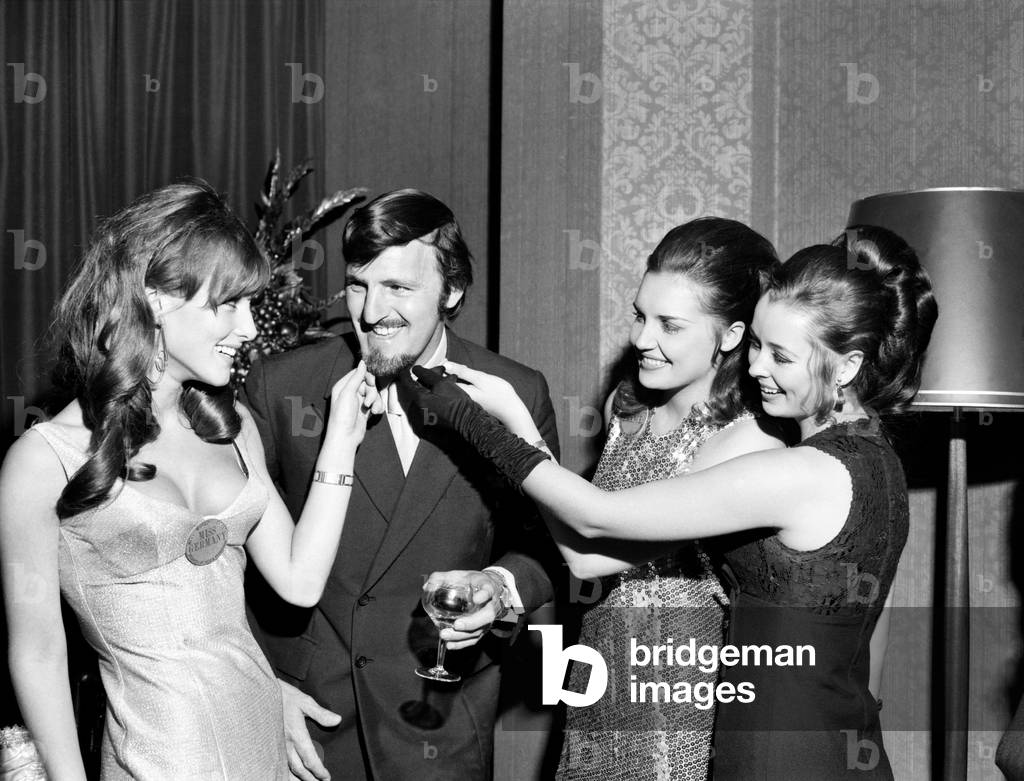 Miss World contestants now in London for the final on the 27th November came face to face with some of Britain's leading sportsmen at a party this evening at the Sportsmans Club, Tottenham Court Road, Three of the girls tug at Jimmy Hill's beard to see if it is real, 1 - r Miss Germany, Christ Margraf (22); Miss France Susanne Angly (18); Miss Gt. Britain, Sheena Drummond (18) from Clackmannanshire, Scotland. November 1969 (photo)