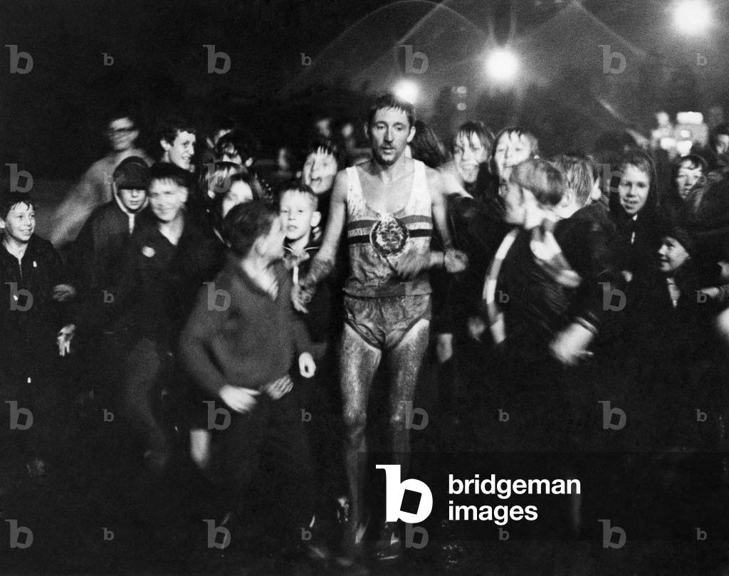 Ron Hill pictured after his record attempt at the 30,000mtrs. record, with crowds around him in the pouring rain, October 1969 (b/w photo)