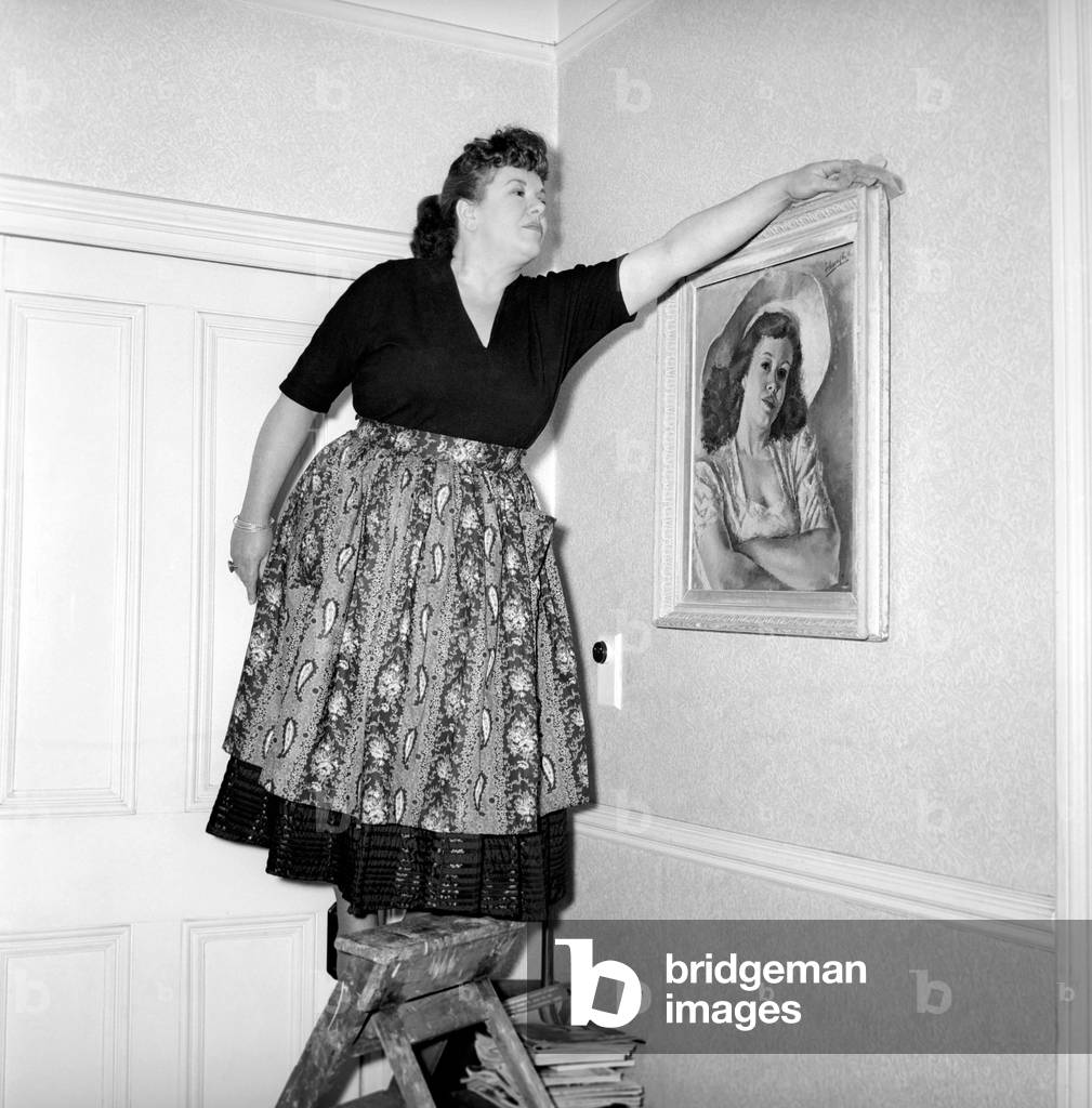 Domestic Life: Woman (Mrs. Olive Haugh) dusting the picture frame, c. 1954 (b/w photo)