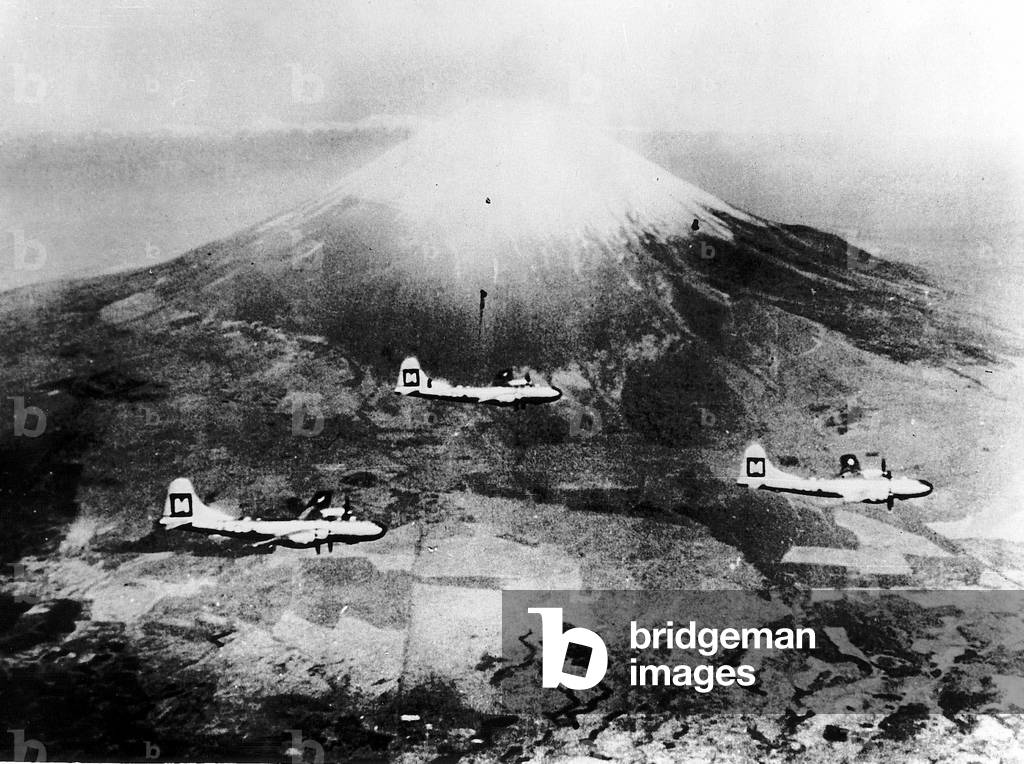 Three Boeing B29 Superfortresses of the US Air Force fly past Mt Fujiyama in attack formation during a strike against Japan in WW2, 1945 (b/w photo)
