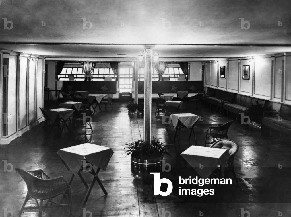 The main lounge of the R101 airship The colour scheme was white panels with gold inlay. The curtains on to the promenade deck were of fine Cambridge blue. The seating arrangements were of small tables, and the chairs were constructed of upholstered green cane wicker. On the walls were paintings, c. October 1929 (b/w photo)