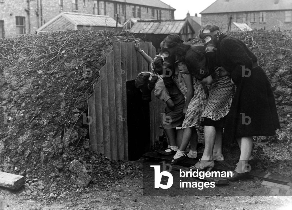 A family wearing gas masks go into an Anderson air raid shelter during the Second World War, 4th September 1939 (b/w photo)