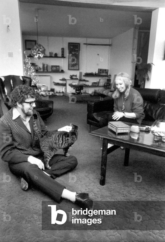 Singer Rolf Harris who lives in Sydenham, Kent, has bought the house adjoining his own modern terrace. He decided he would like to enlarge the three bedroomed house and knocked down the brick wall between the houses, himself. Rolf and his sculptress wife Alwen live their with their five year old daughter Bindi. Rolf with his wife Alwen sitting in the new house. In background is the old house. December 1969