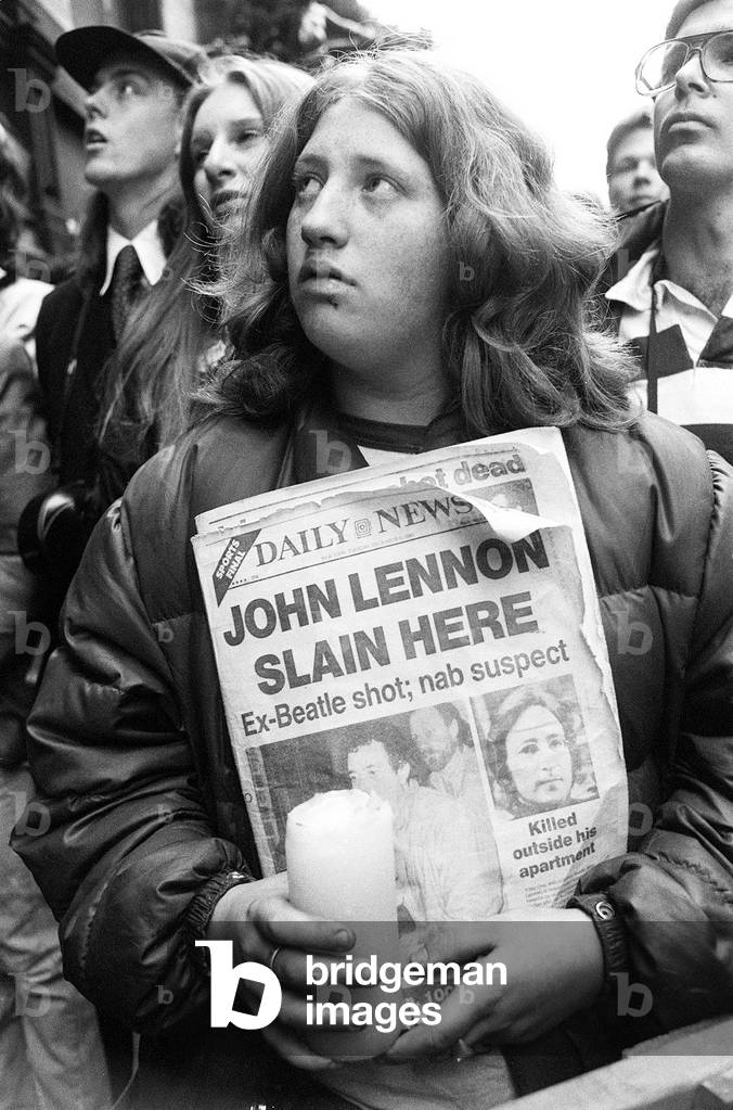 John Lennon fans gather to pay there last respects outside the Dakota Apartments in New York, the spot where the former Beatle was shot dead by Mark Chapman. 9th December 1980 (b/w photo)