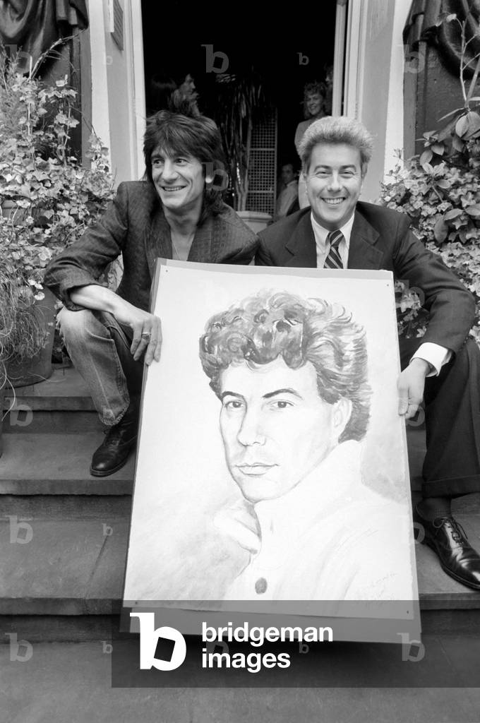 Rolling Stones: Ronnie Wood holds a painting of author Ken Follett who stands next to him. September 1987
