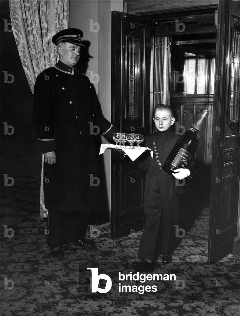 Little Richard - all 4ft. 2in. of him - takes a bottle almost as big himself past a 6ft. commissionaire. Richard will become Britain's tiniest bell boy, unless a shorter one is found before January 21. January 1964