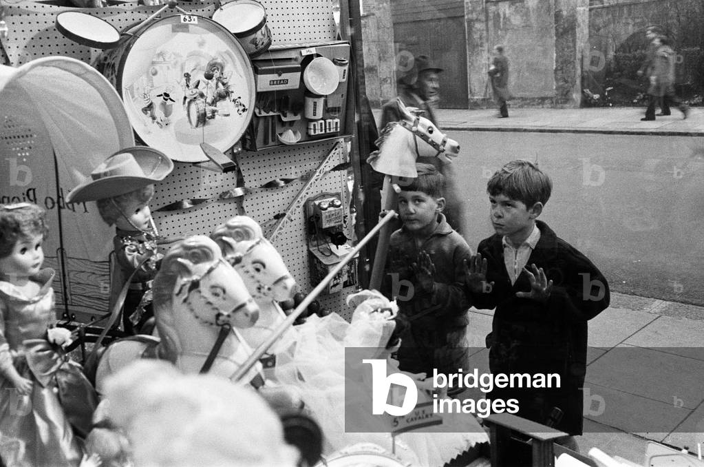 Children look longingly at toys into shop window at Christmas, 16th December 1960 (b/w photo)