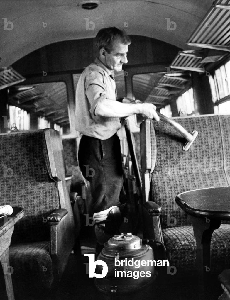 Mr. Frank Baley vacuums seats while cleaning a carriage ready for another journey on 10th September 1971 (b/w photo)