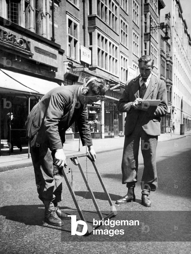 Two men who work for the GPO at work with a mine detector as they try to find a cable of which they have no record in Holborn, London, 8th May 1949 (b/w photo)