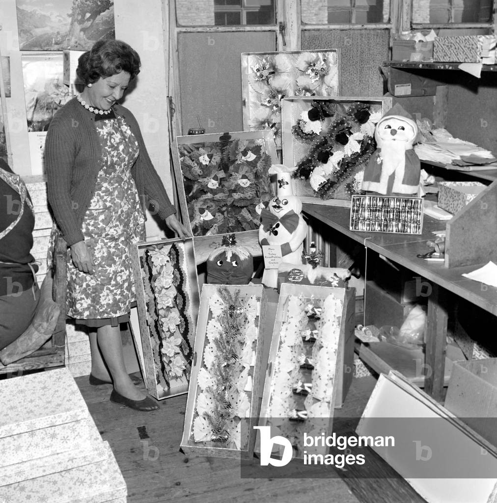 General scene in and around a Christmas cracker factory, where women construct and quality control the manufacture of the crackers, c. 1955 (b/w photo)