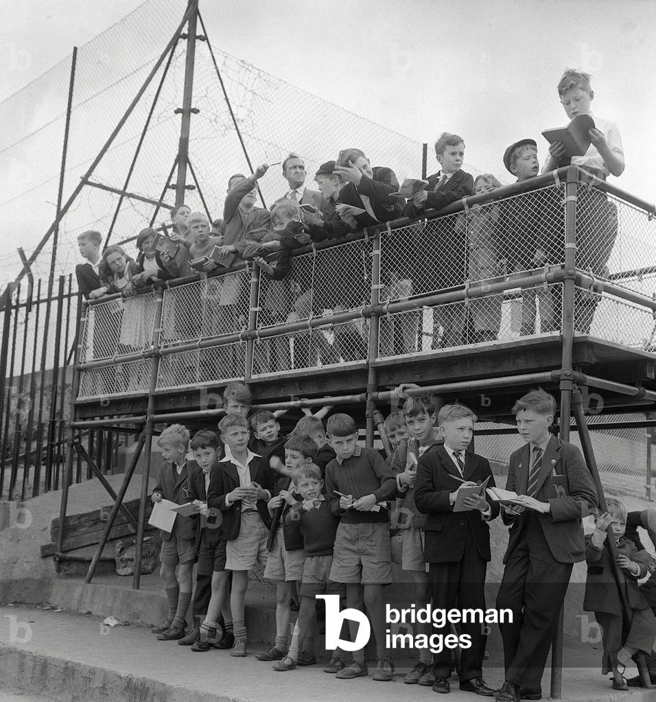 Children Train Spotting, July 1960. Children spend many hours watching the trains go by from Finsbury Park. They have at their disposal a train-spotters platform with times of trains that travel from Kings cross to the North of England and Scotland, July 1960 (b/w photo)