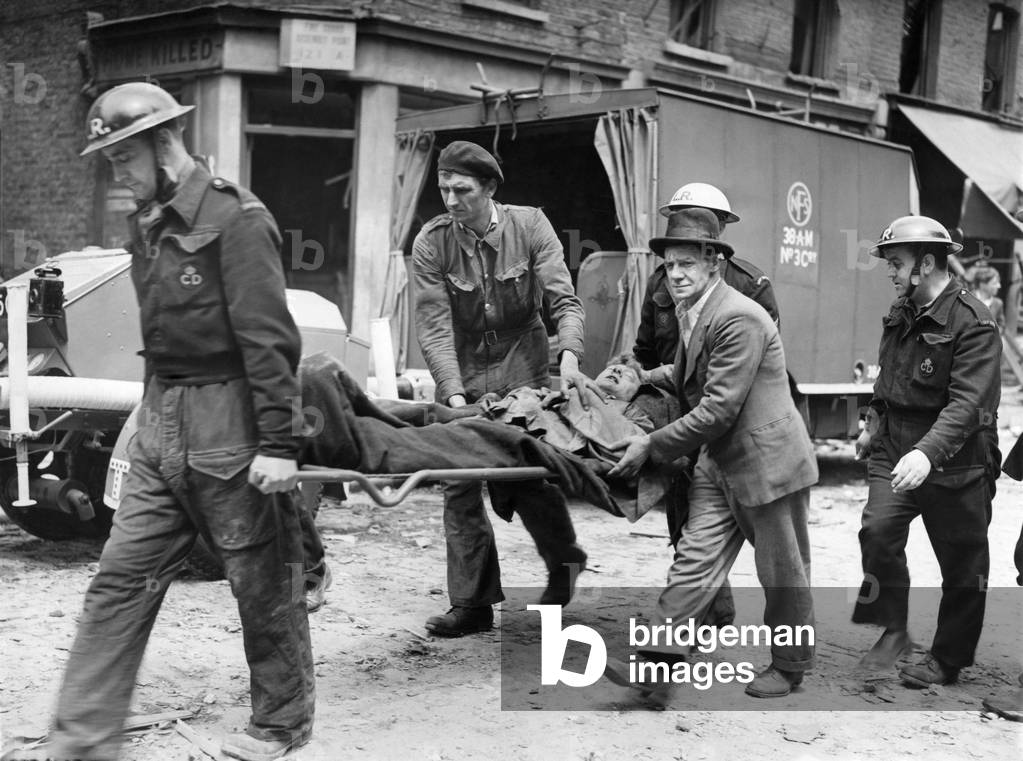 Robot plane damage at East Lane, Walworth. A casualty being taken to ambulance with a friend comforting him after he had helped to get him out. 
June 1944