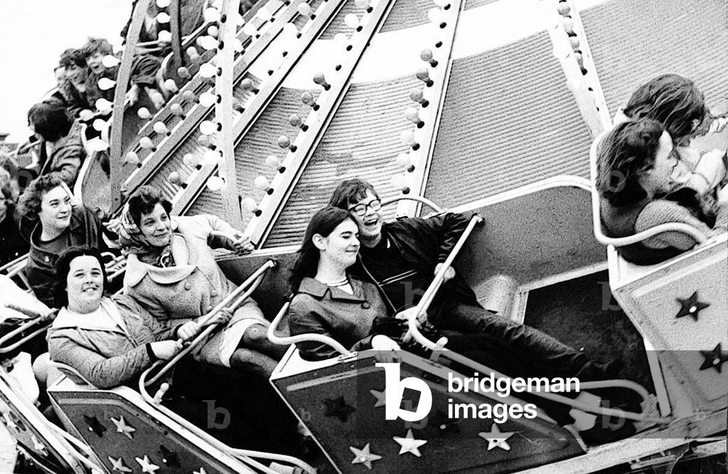 It's fast, but it doesn't seem a bit frightening for these fair goers at the Hoppings on Newcastle Town Moor, 1969 (b/w photo)