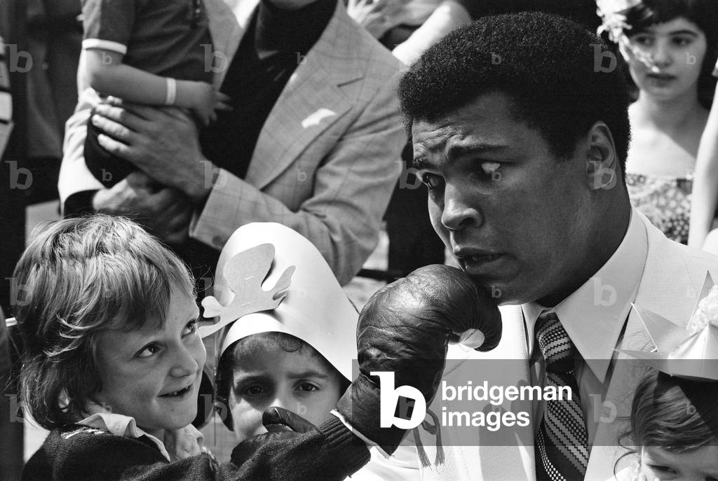 World Heavy-weight boxing champion, Muhammad Ali presented a coach on behalf of the Variety Club of Great Britain (the children's charity organisation) to the Hospital for sick children, Great Ormond Street, today. 11th August 1977 (b/w photo)