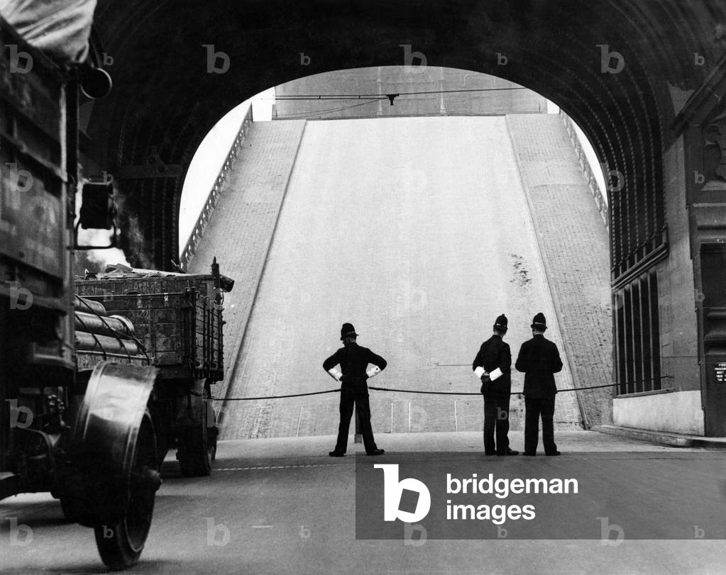 One of London's Famous Sites - The Tower Bridge is nothing new, we all have seen it, but how many of us would pass by without watching if the bridge should happen to open while we were near it. Circa 1933.