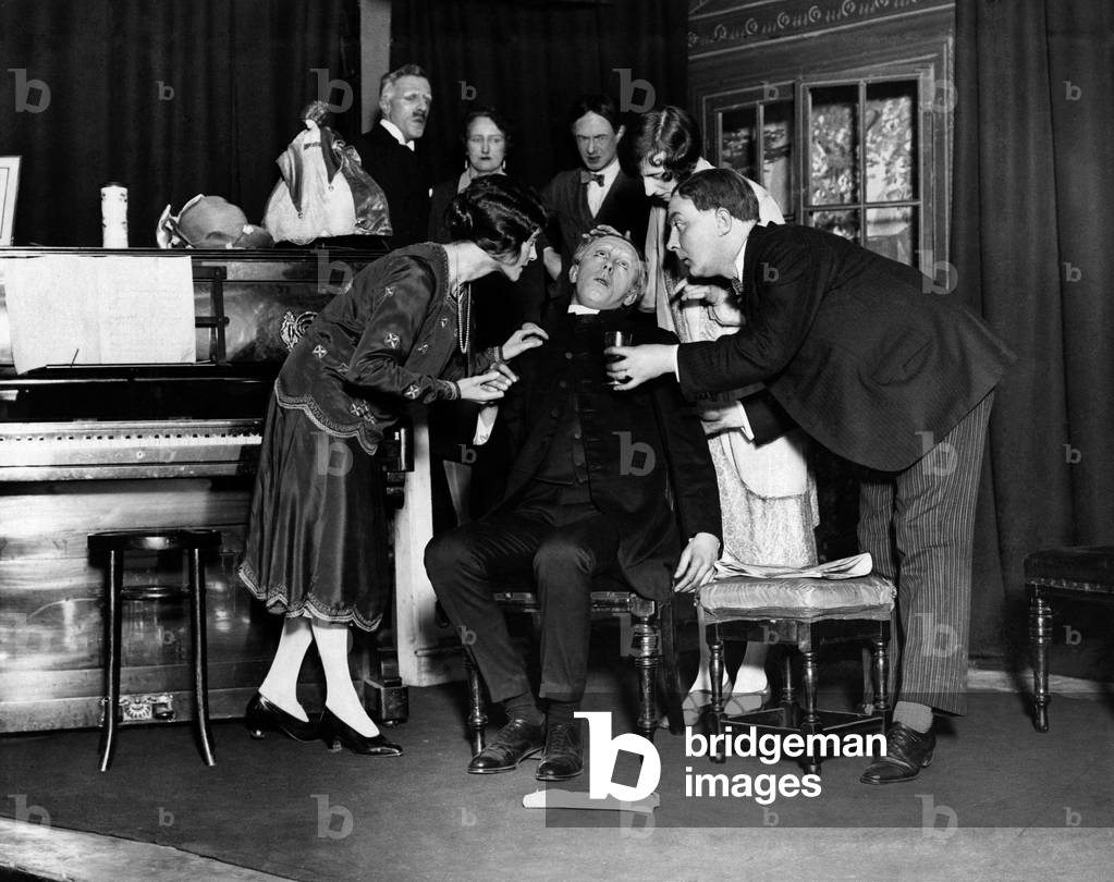 A scene from the play Nothing But the Truth at the Blackfriars Theatre. A man is offered a drink after fainting. February 1928