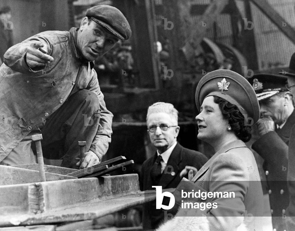 Queen Elizabeth The Queen Mother talking to a shipyard worker, during her visit to the North, 9th April 1943 (b/w photo)